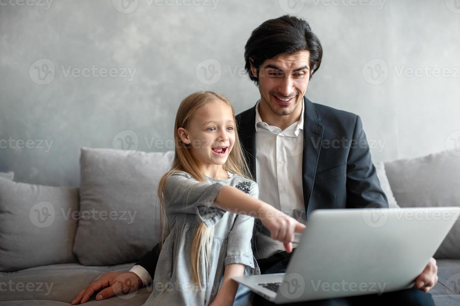 Happy little girl watching a movie on the computer with her father photo