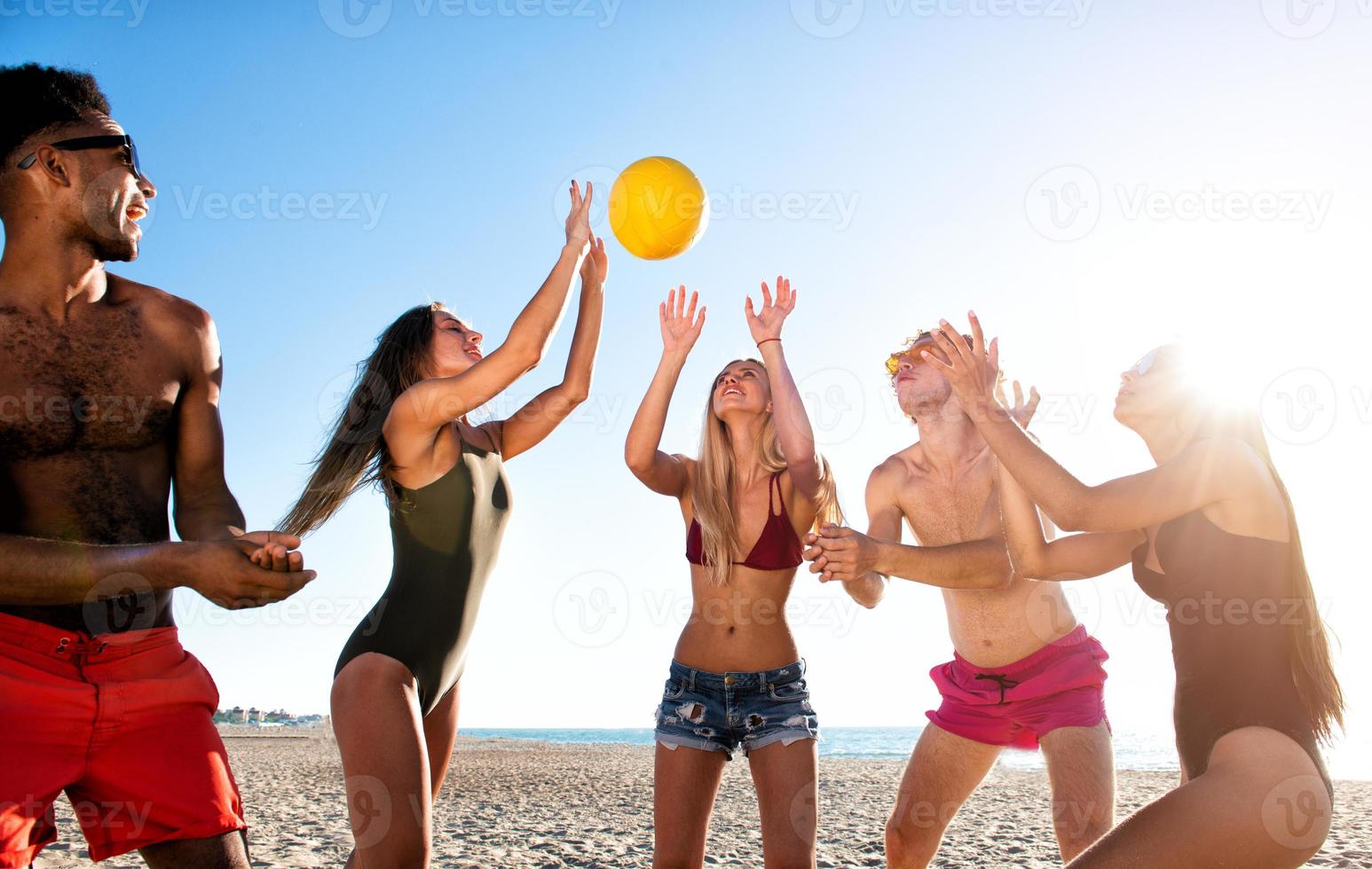 Group of friends playing at beach volley at the beach photo