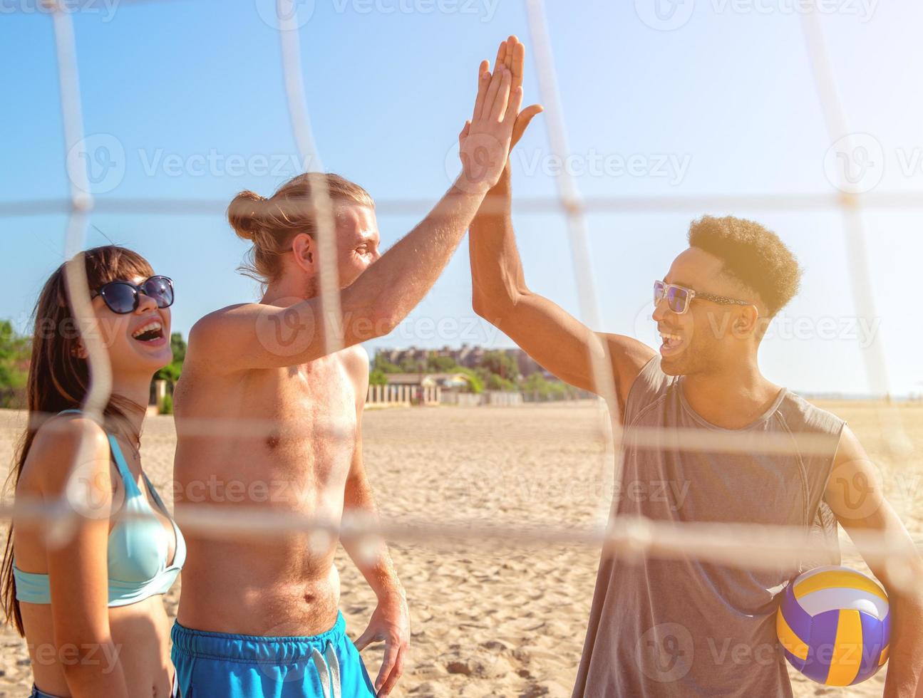 Group of friends playing at beach volley at the beach photo