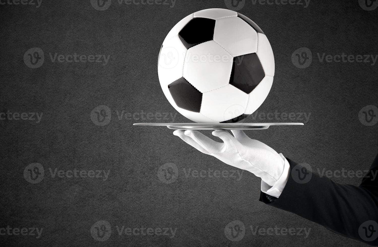 Waiter that holds a tray with soccer ball. Concept of first class service on soccer photo