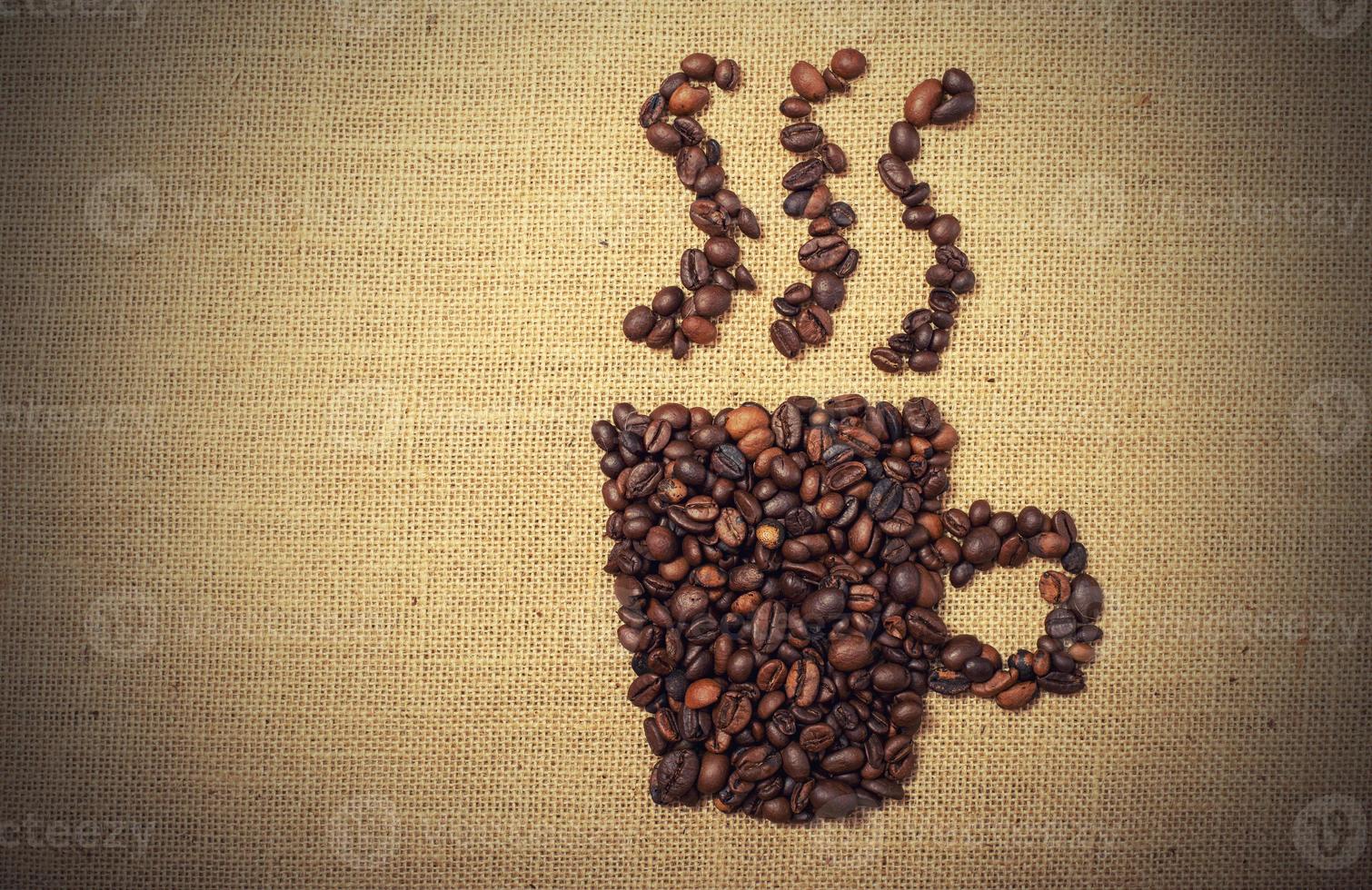 Coffee beans shaped as cup over a jute cloth photo