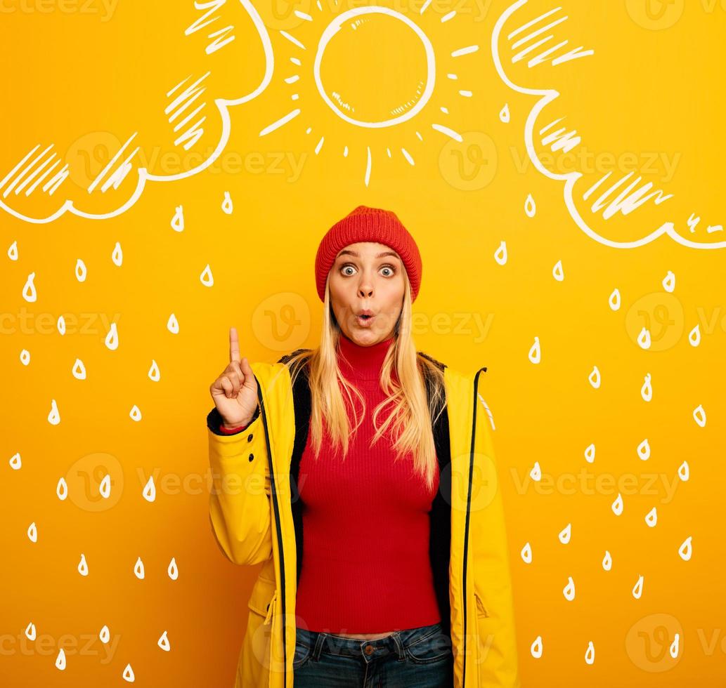 Girl indicates the sun between the clouds above. Amazed and shocked expression. Yellow background photo