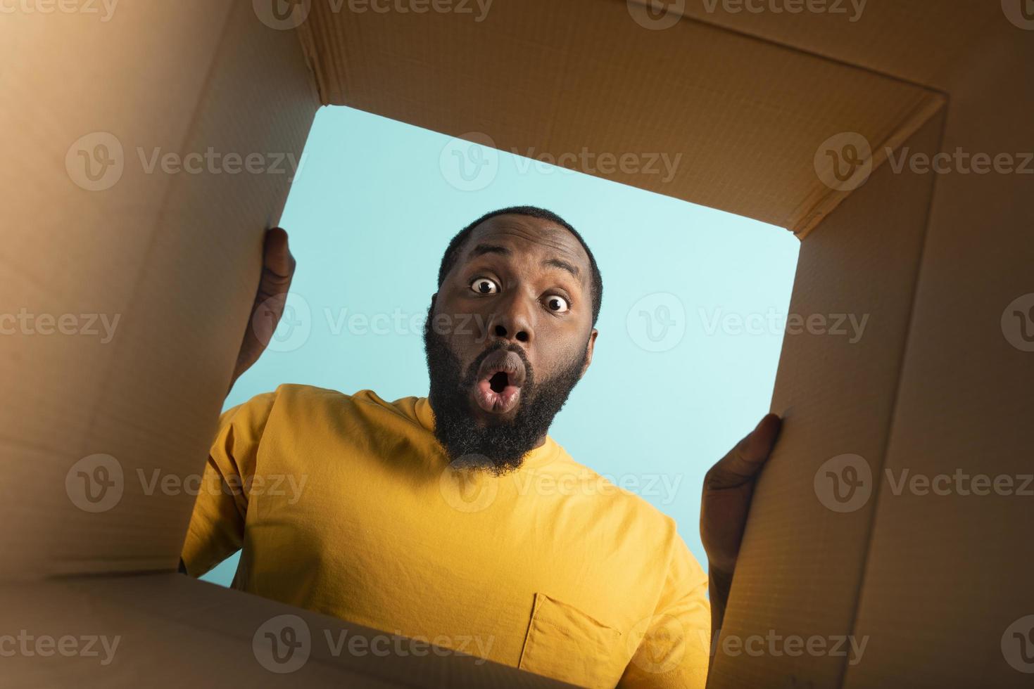 Happy boy receives a package from online shop order. happy and surprised expression. Blue background. photo