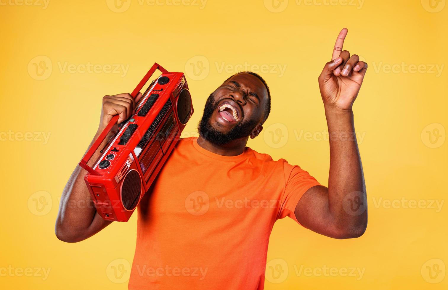 Boy ears the music with an old stereo and dances. emotional and energetic expression. yellow background photo