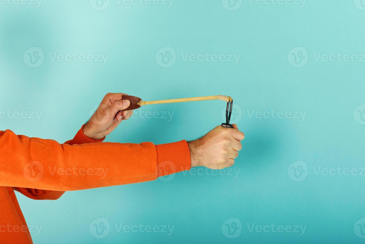 Man ready to throw from the slingshot something. cyan background photo