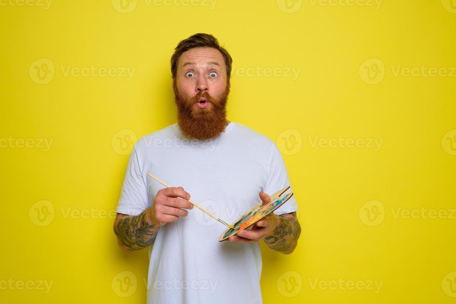 Wondered man with beard and tattoo is ready to draw with brushes photo