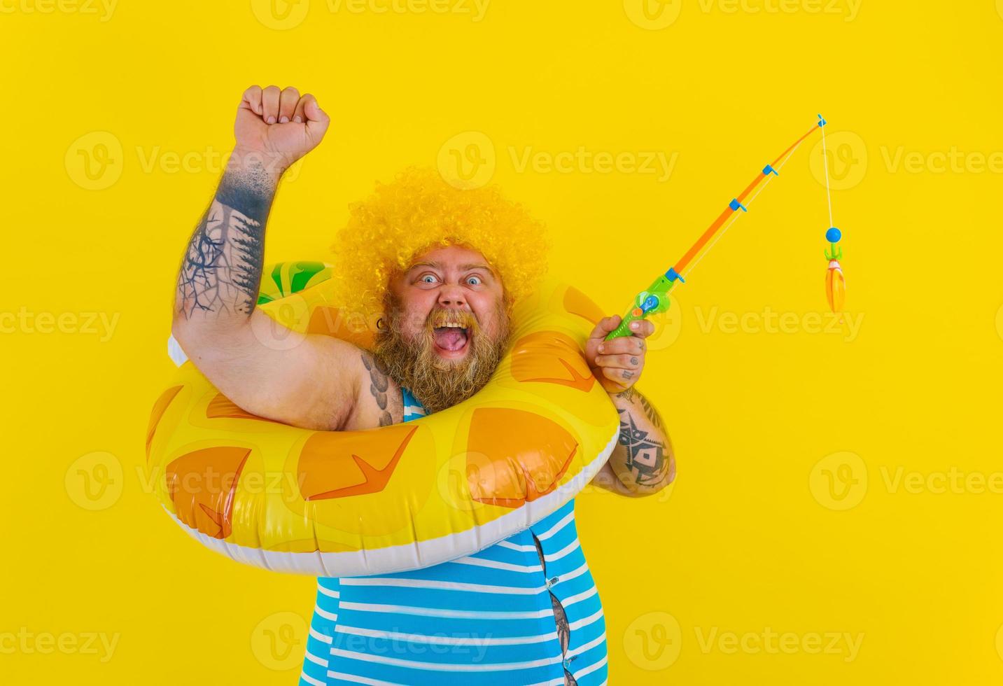 Fat happy man with wig in head plays with the fishing rod photo