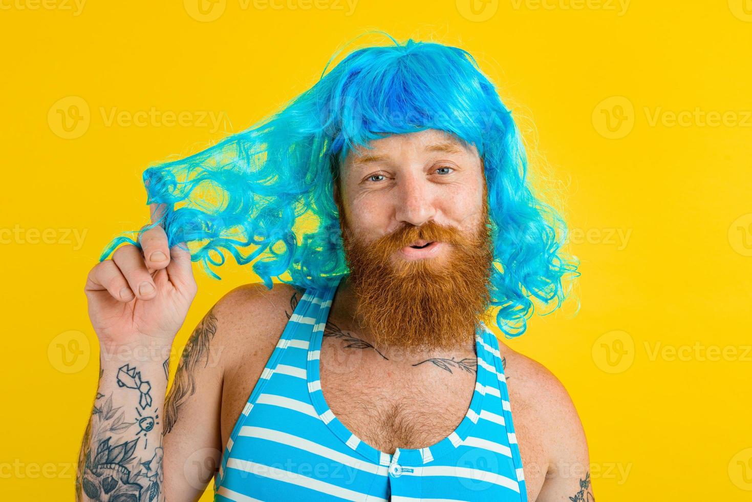 Happy man with life buoy, swimsuit and blue wig acts like a happy woman photo