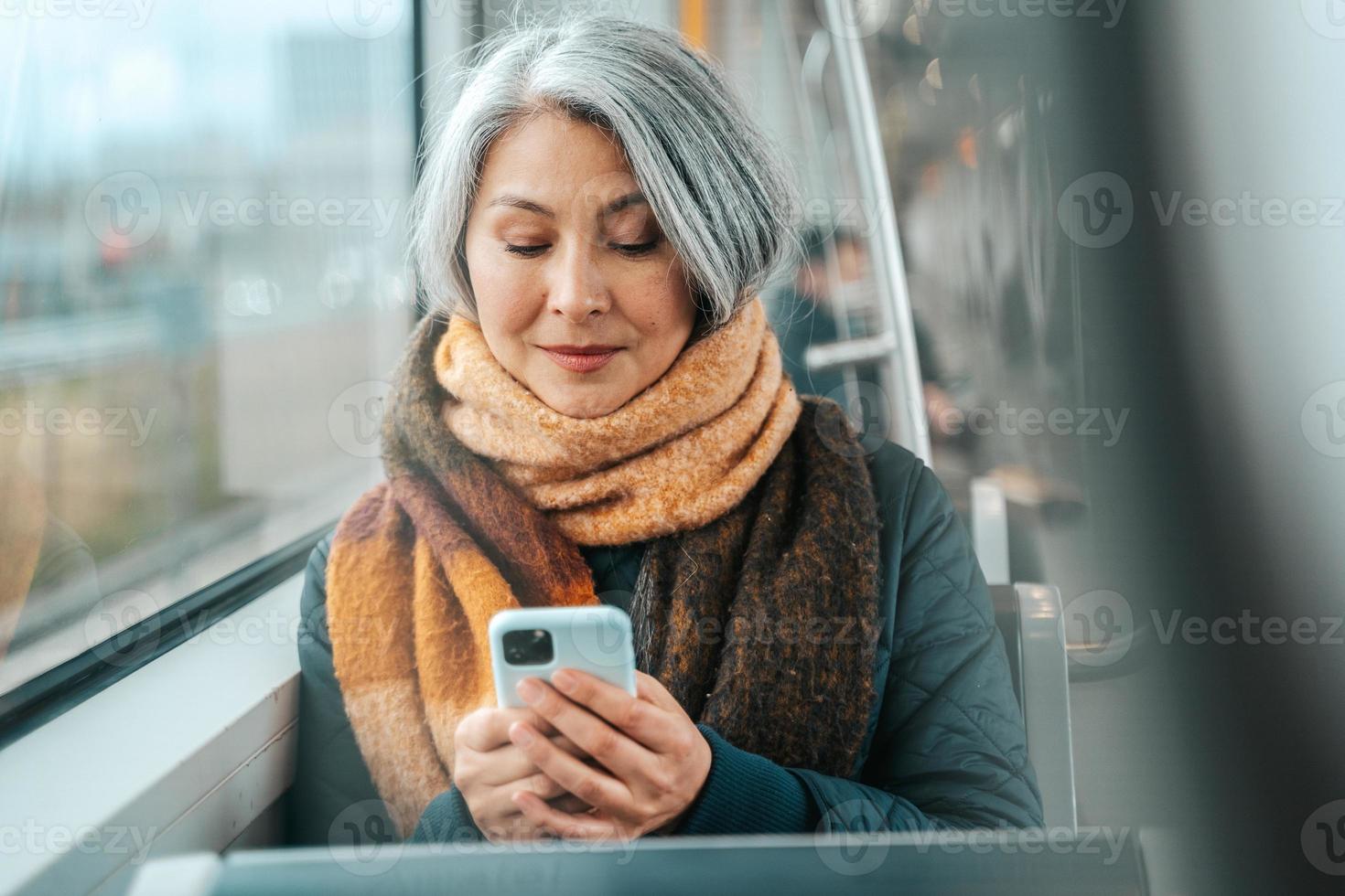 Senior woman send message with a mobile phone in a train photo