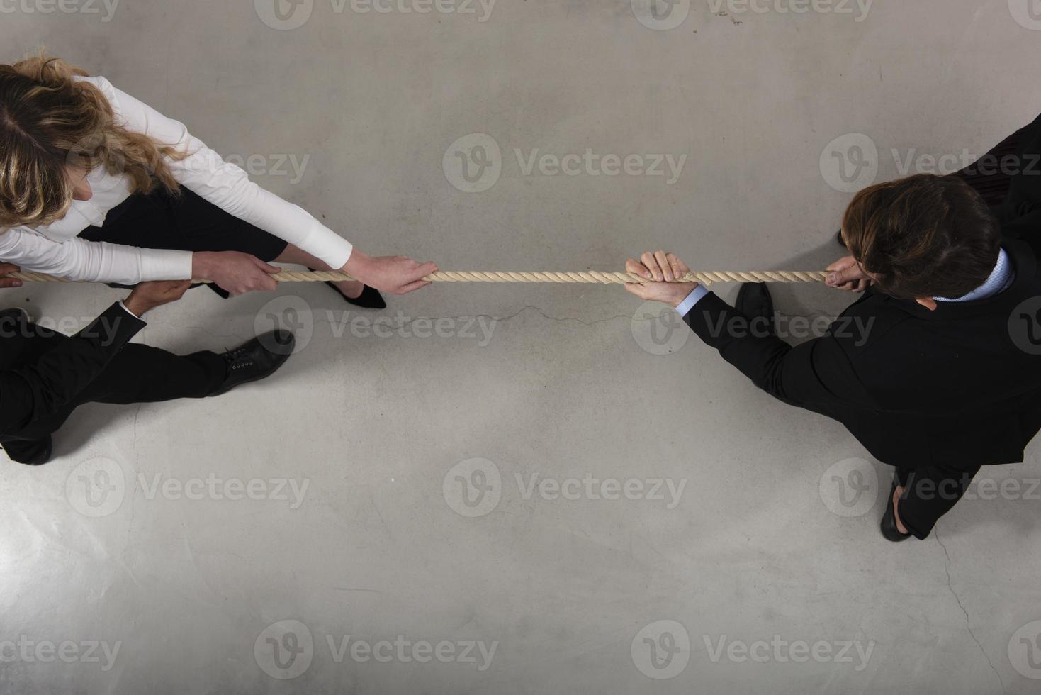 Rival business man and woman compete for the command by pulling the rope photo