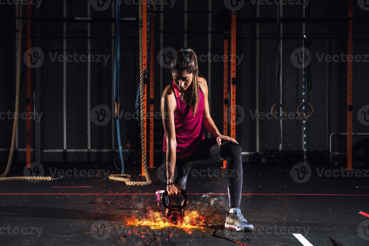 Athletic girl works out at the gym with a fiery kettlebell photo