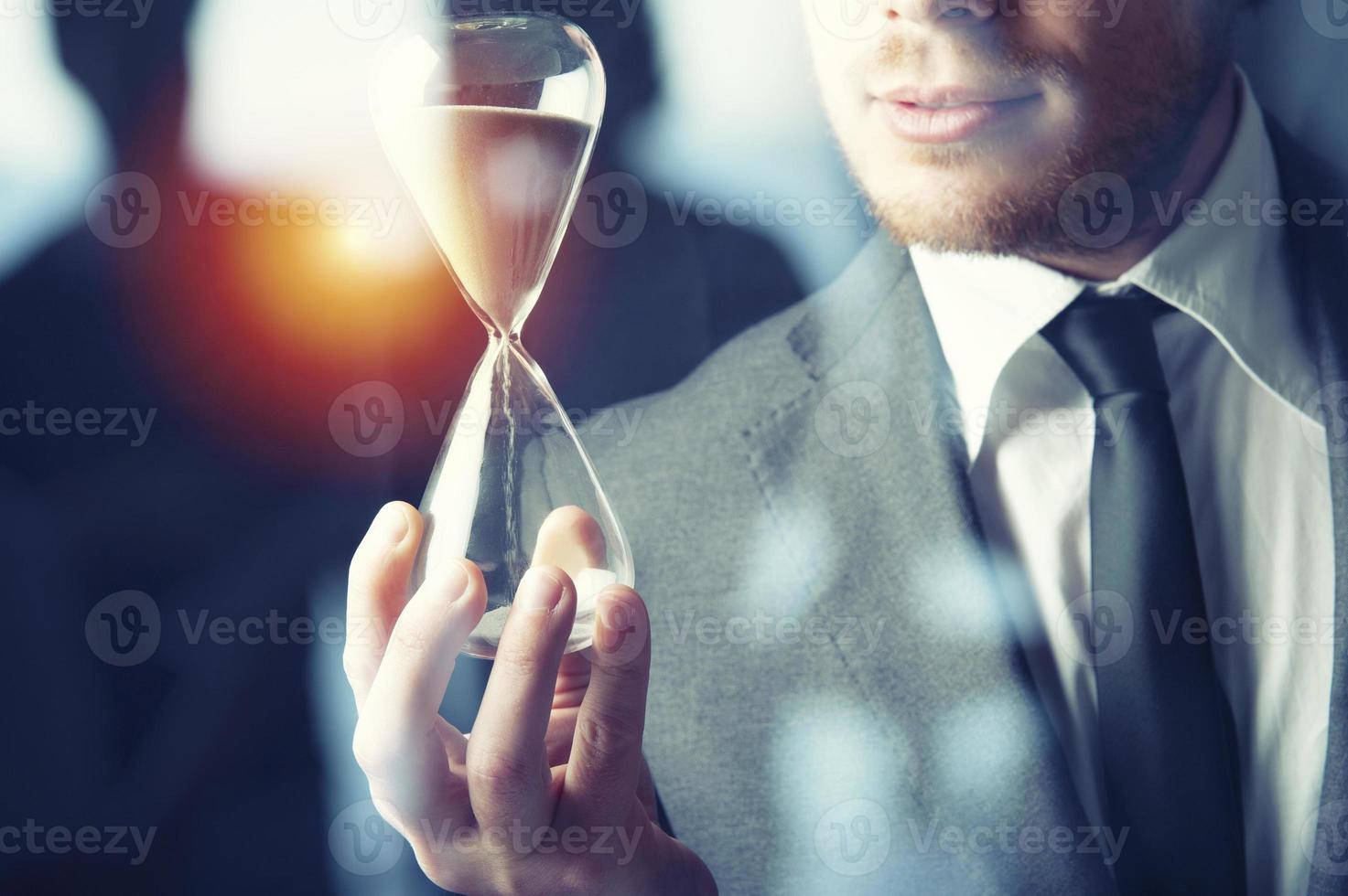 Businessman holding a hourglass. Concept of deadline in business photo