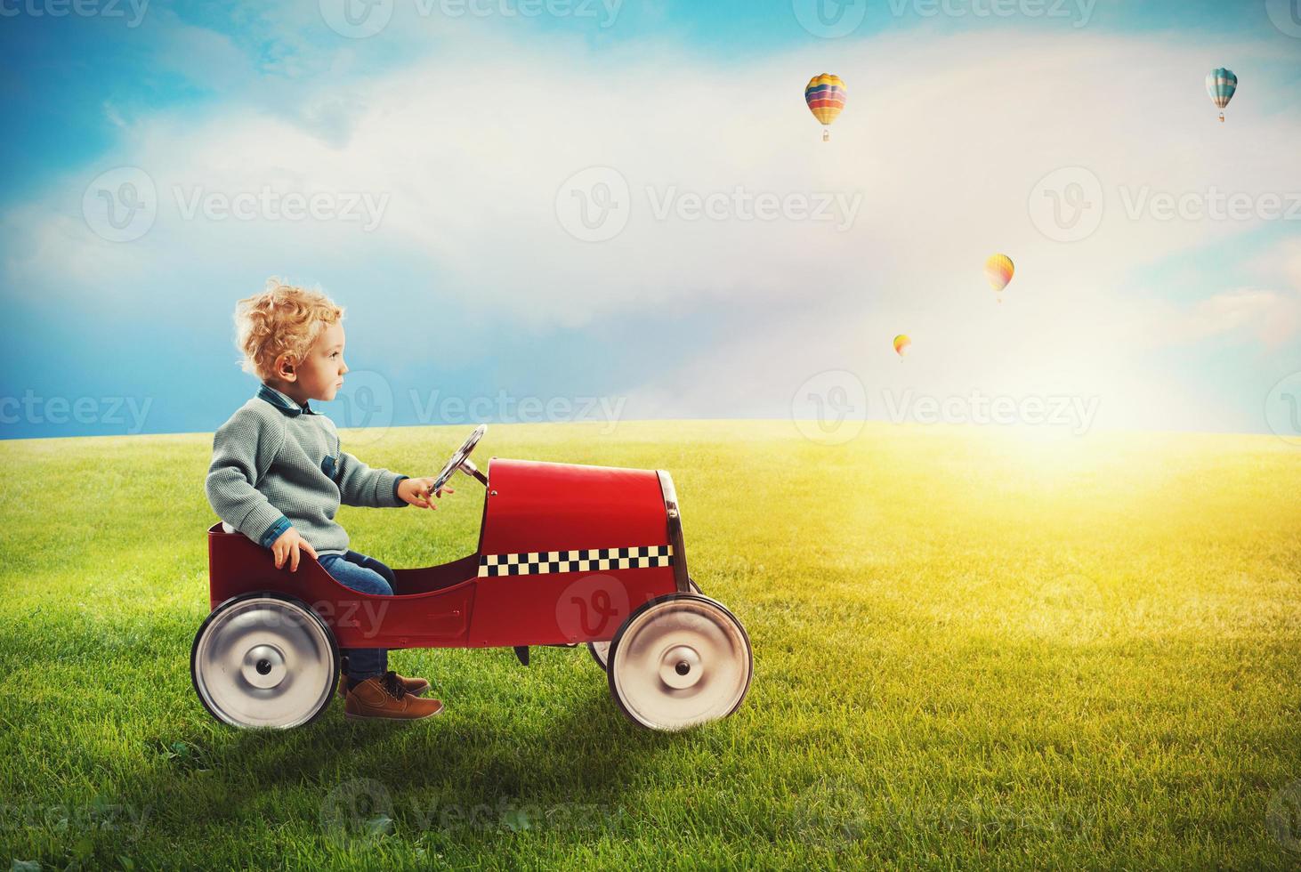 Child with car plays in a green field photo