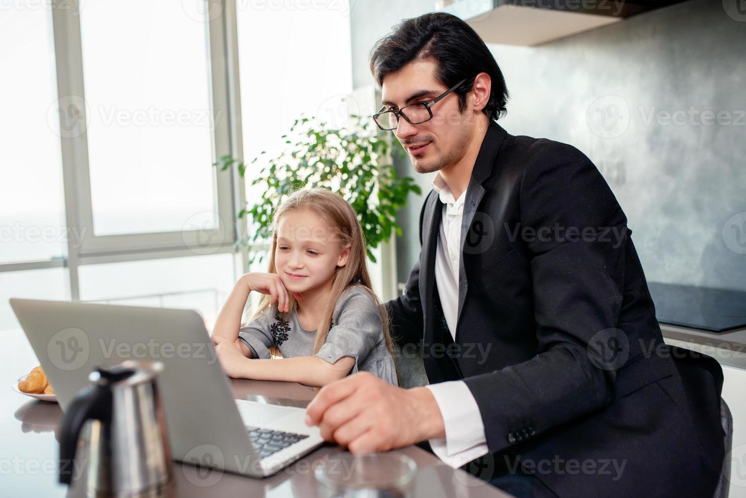 Happy little girl watching a movie on the computer with her father photo