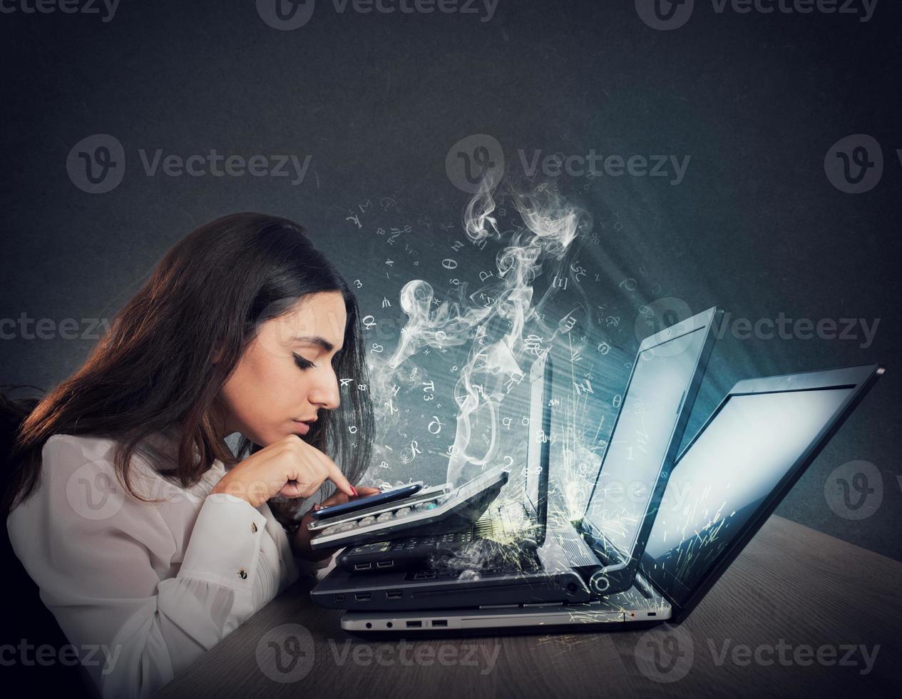 Businesswoman works with multiple devices, smartphone, calculator and laptops. Concept of overwork and stress photo