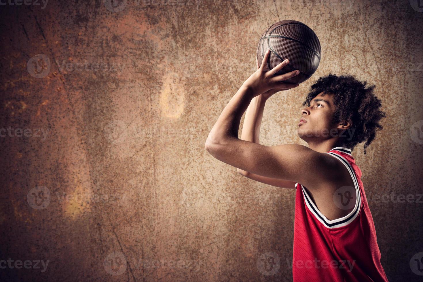 Basketball player throws the ball on grunge brown background photo