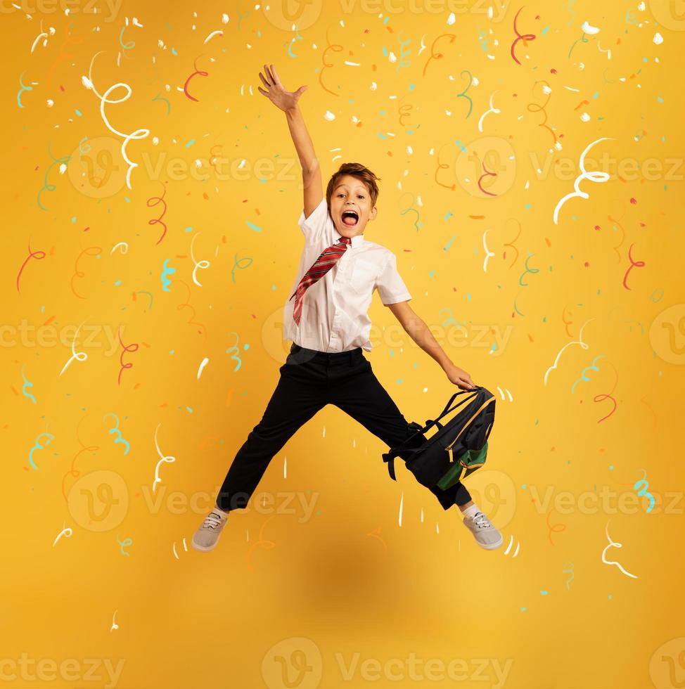 Young boy student jumps high happy for the promotion. Yellow background photo