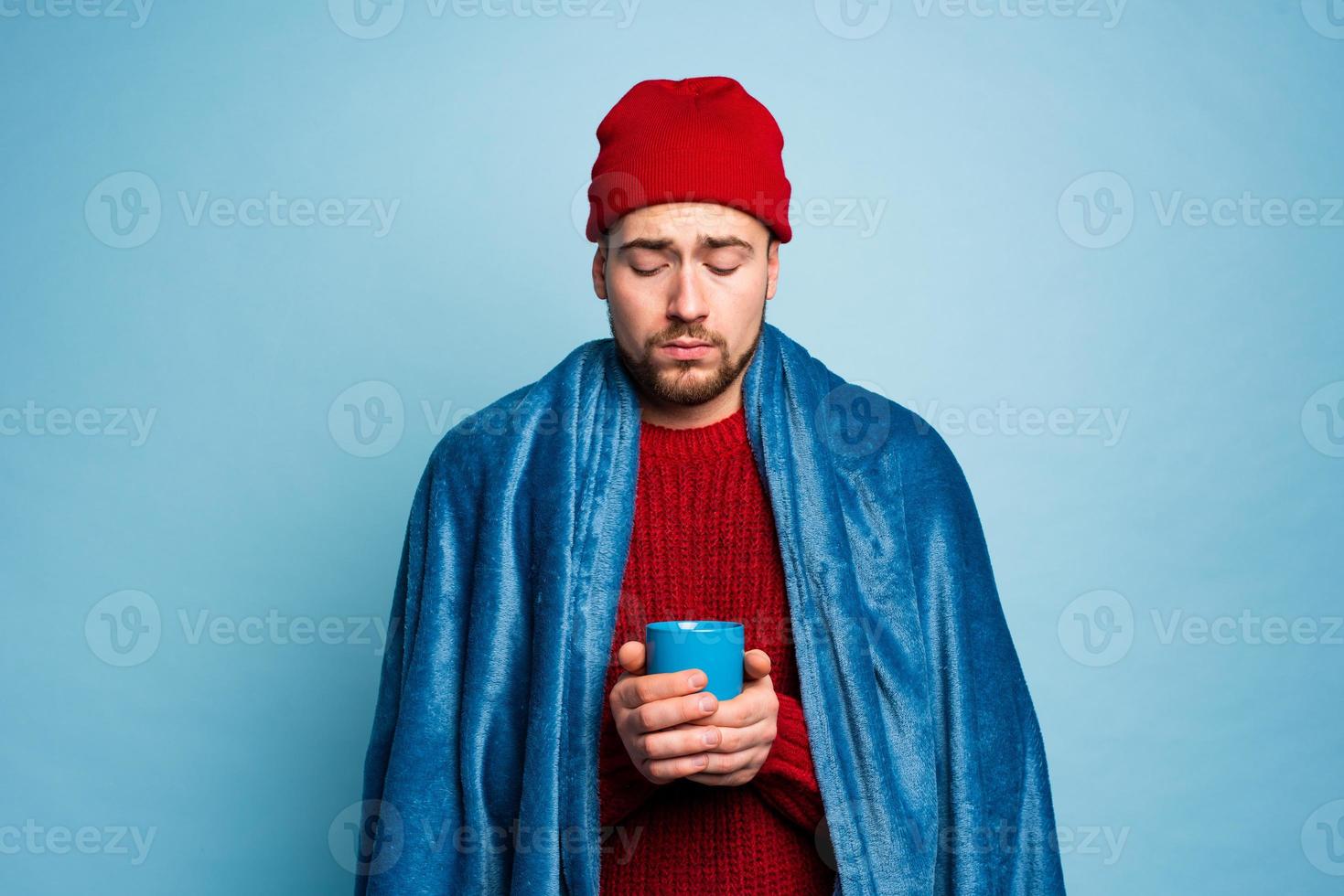 Boy caught a cold and drinks hot the. Cyan background. Concept of illness photo