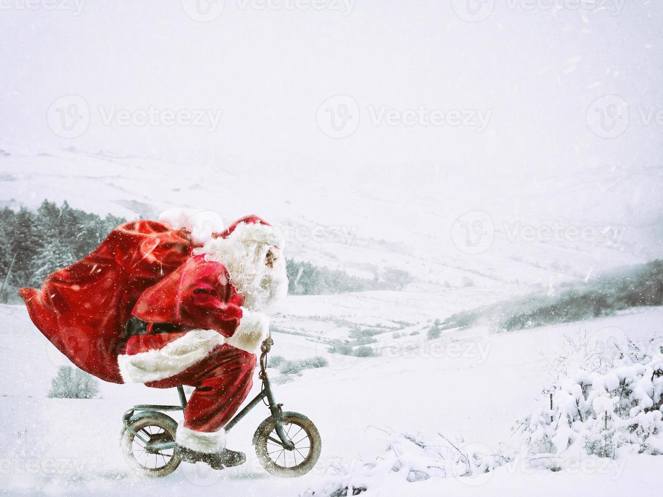 Papa Noel claus en un pequeño bicicleta en un invierno paisaje debajo el nieve foto