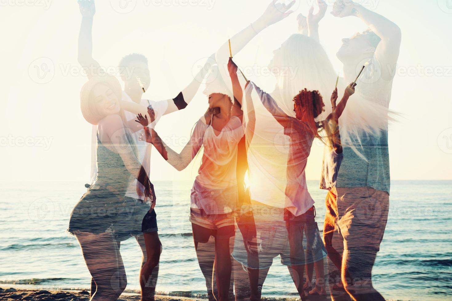 Happy smiling friends running at the beach with sparkling candles photo