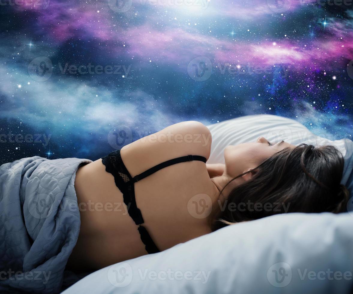 Girl sleeps in a cozy bed during the night with space background. Concept of relax and rest. photo