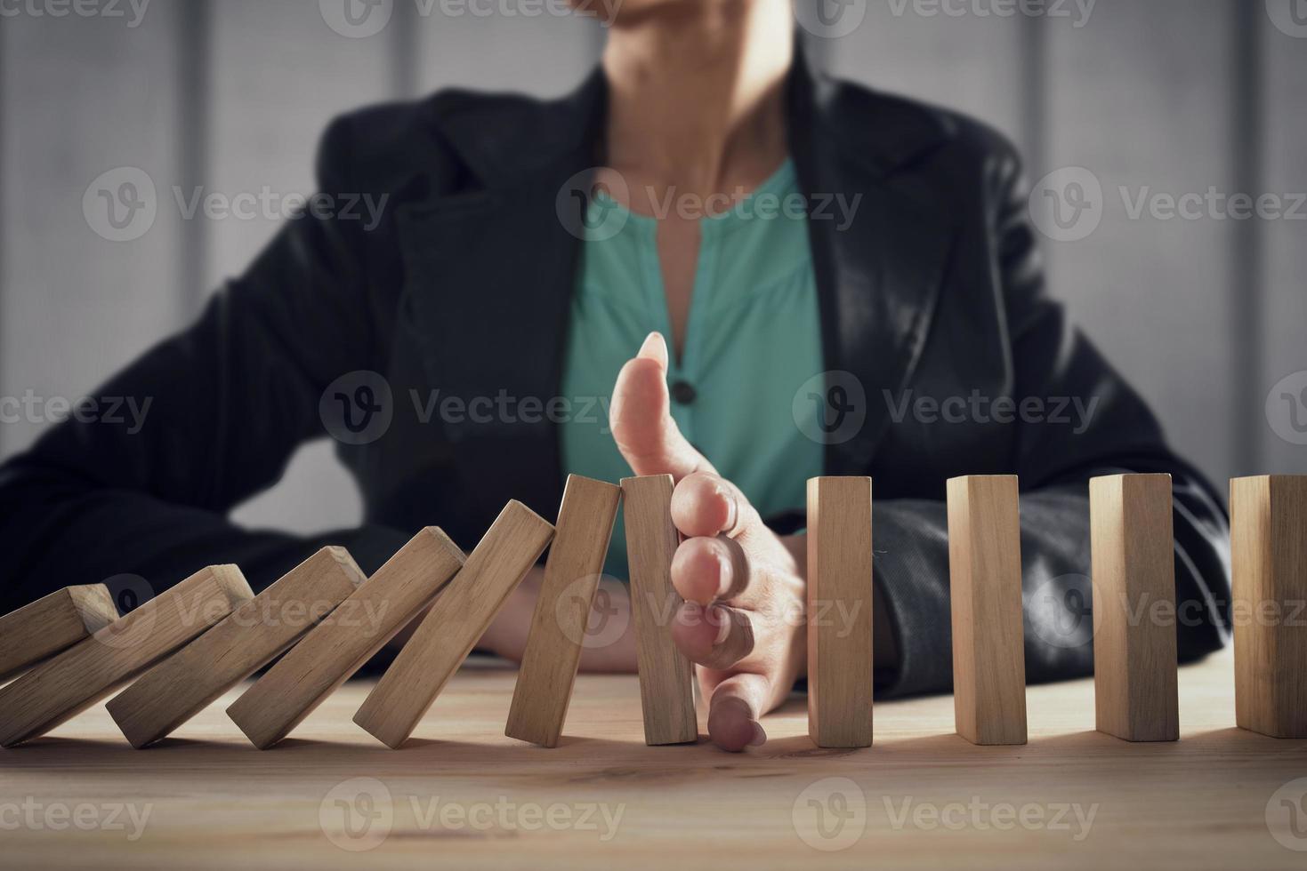 Businesswoman stops a chain fall like domino game. Concept of preventing crisis and failure in business. photo