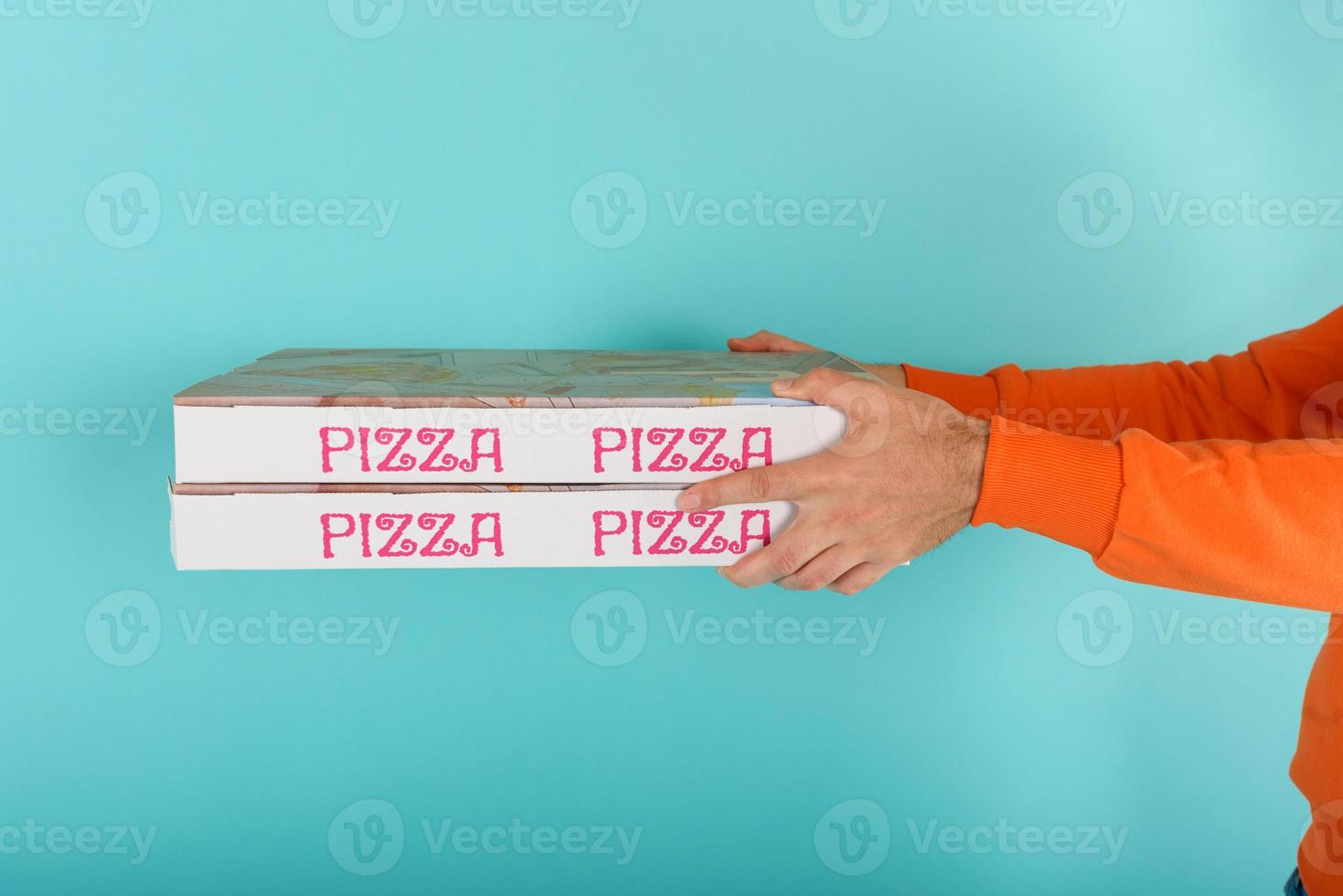 Deliveryman holds bizza boxes ready to be delivered . cyan background photo
