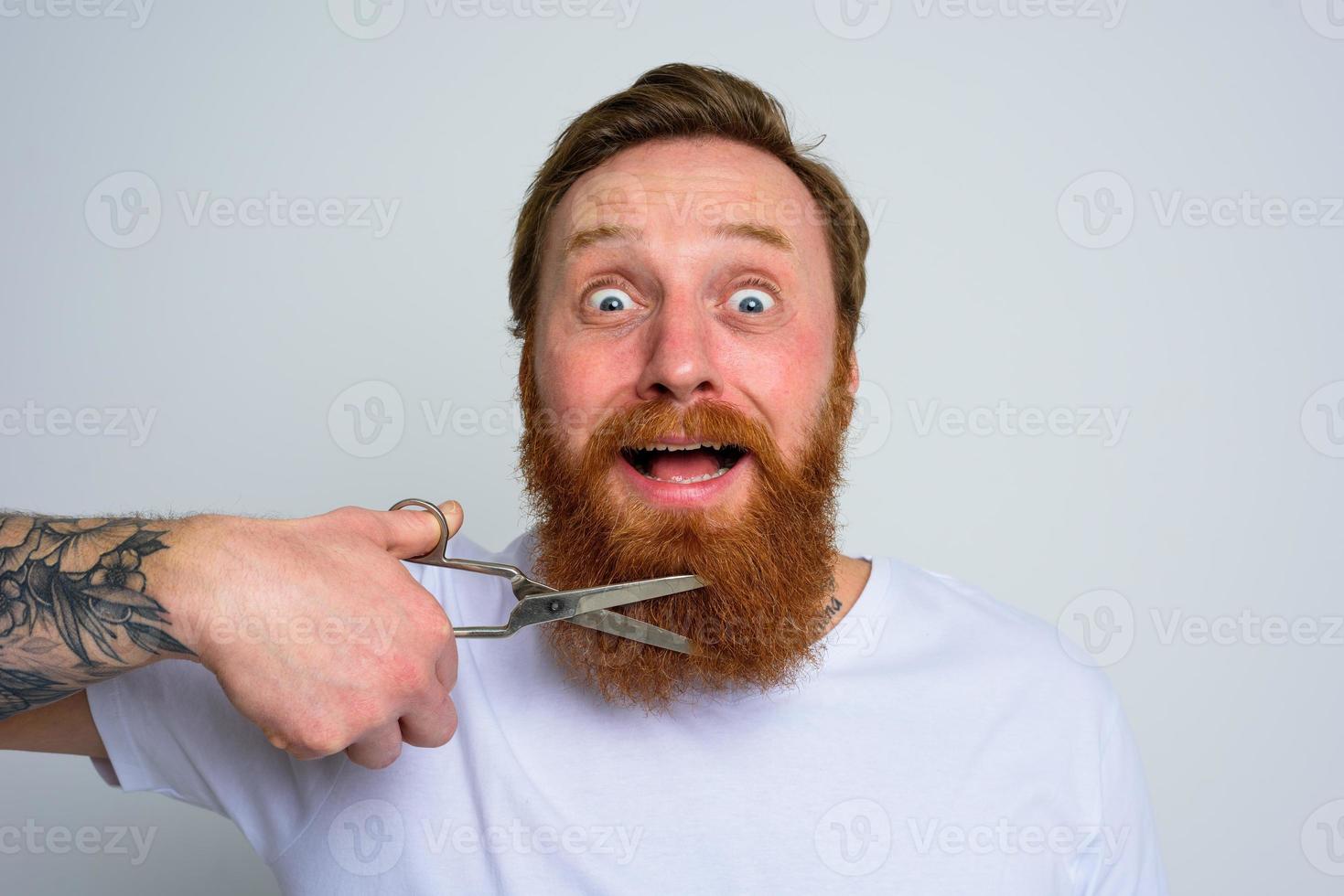 Unhappy man with scissors doees not want to cut the beard photo