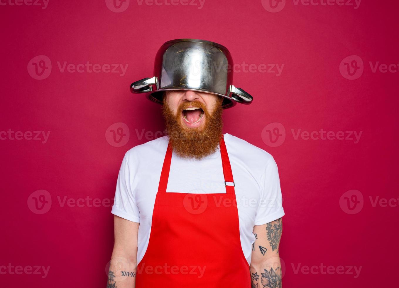 Happy chef with beard and red apron plays with pot photo
