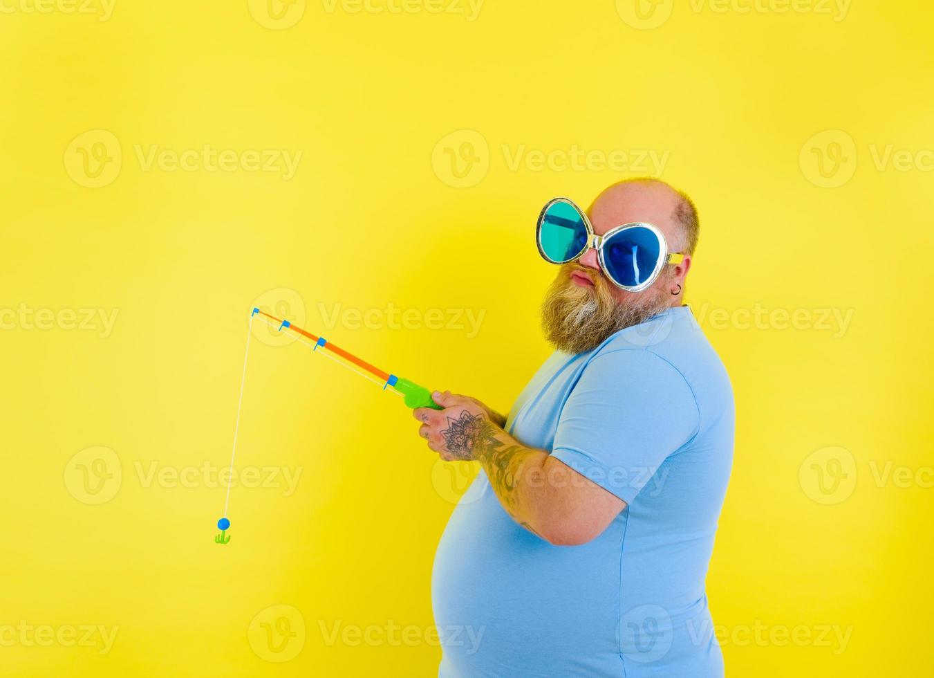 Fat man with beard and sunglasses is unhappy with the fishing rod photo