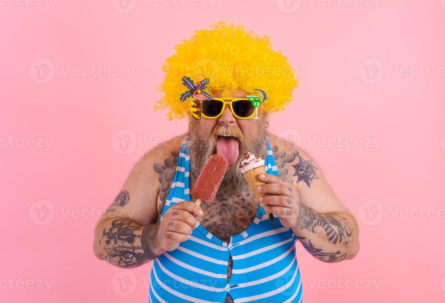 Fat man with beard and wig eats a popsicle and an icecream photo