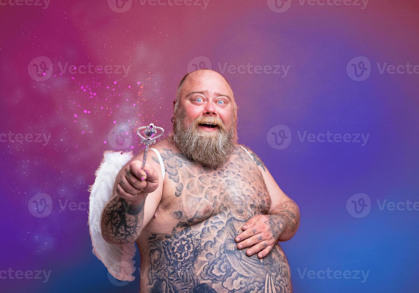 Fat happy man with beard ,tattoos and wings acts like an magic fairy photo