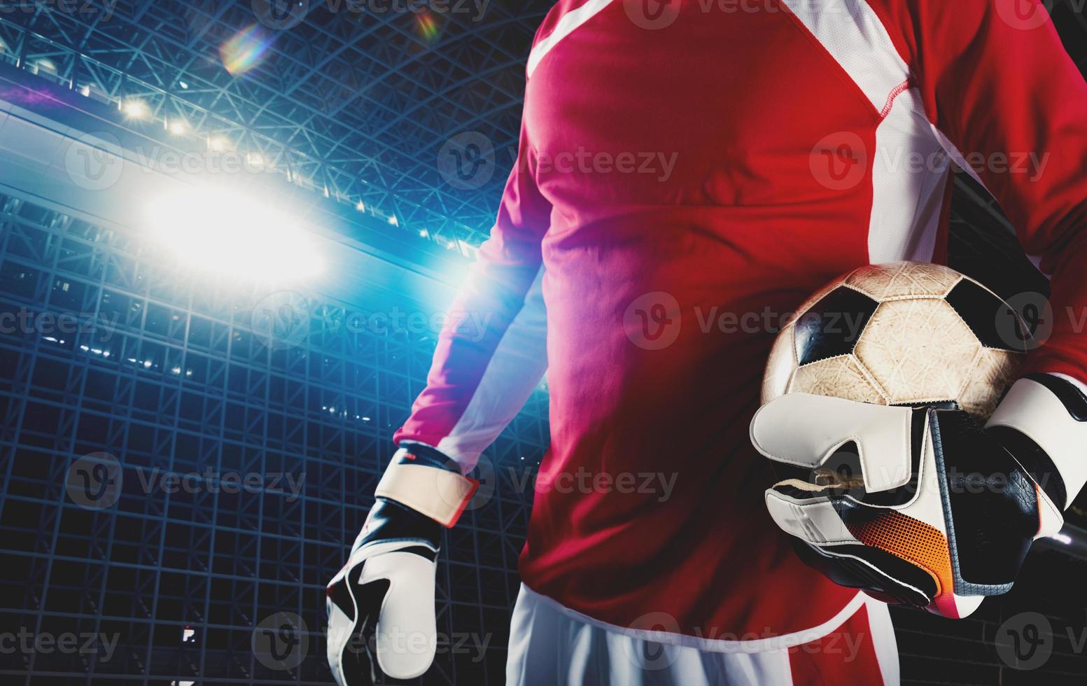 Goalkeeper holds the ball in the stadium during a football game photo