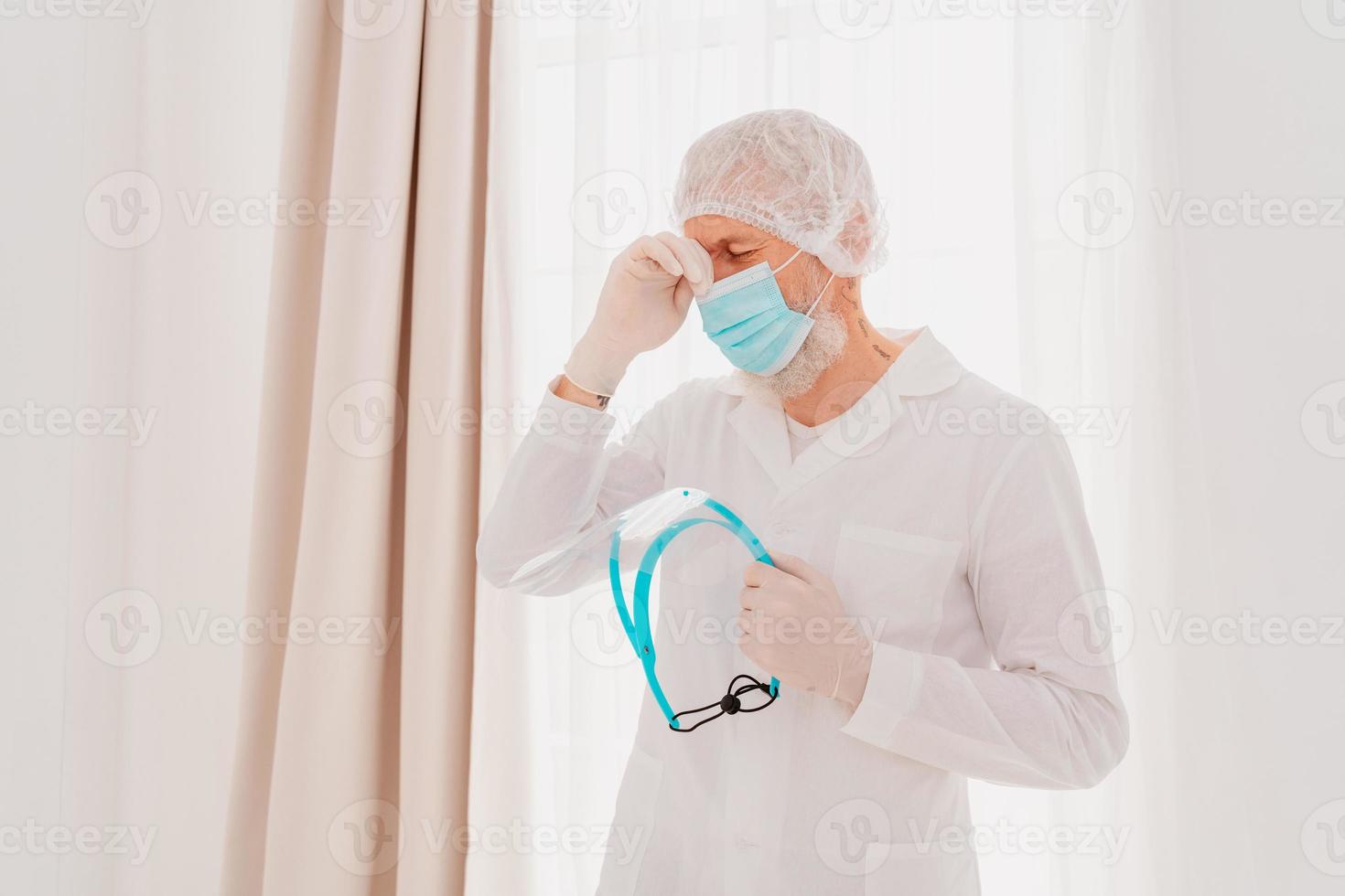 Doctor with face mask and face protector is tired about the covid-19 virus pandemic photo