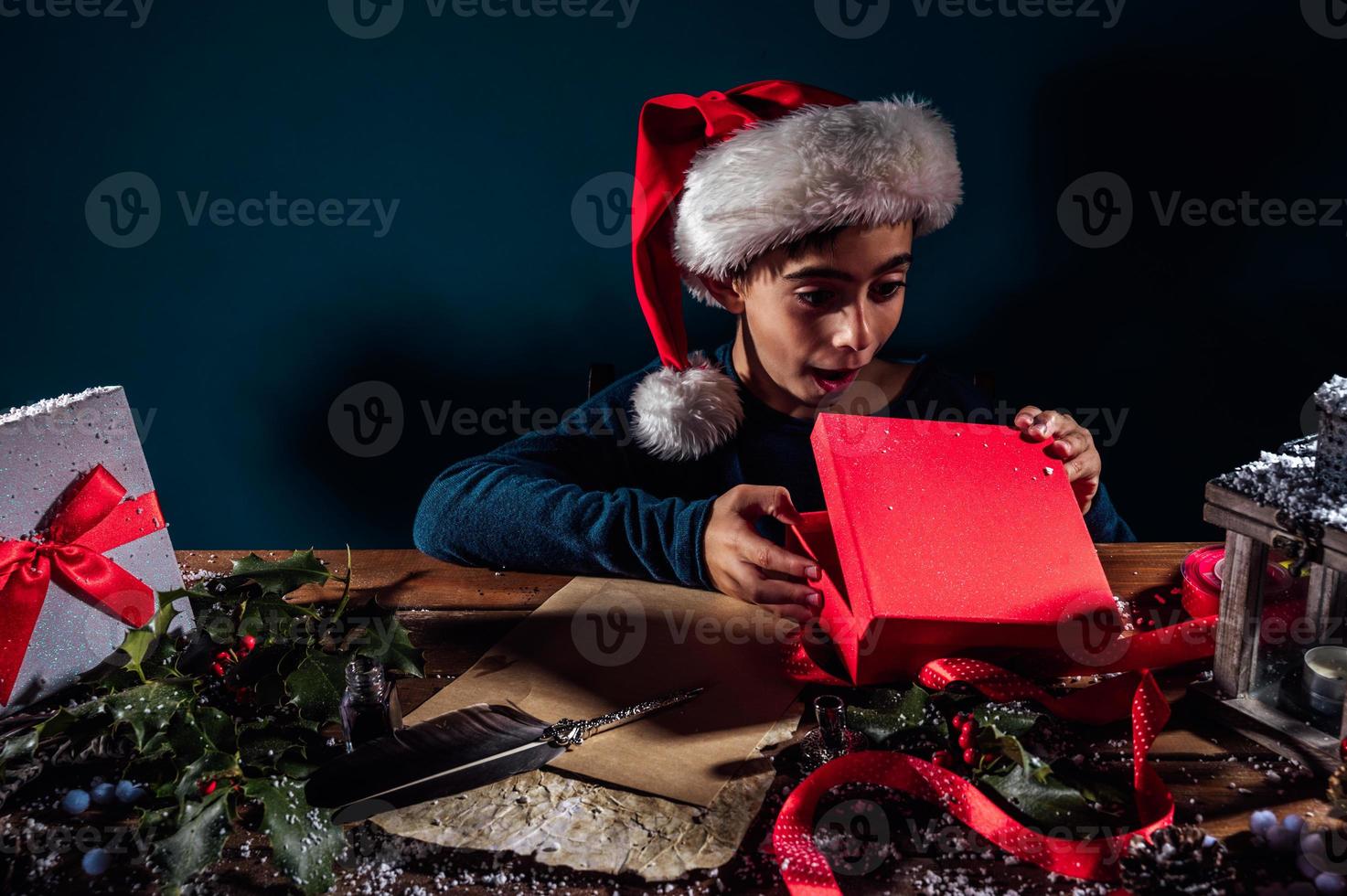 Child with Christmas hat writes a letter to santa claus for gifts photo