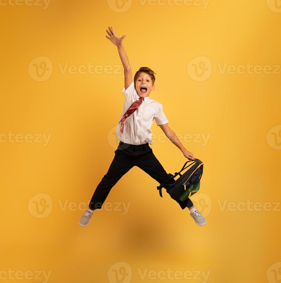 Young boy student jumps high happy for the promotion. Yellow background photo