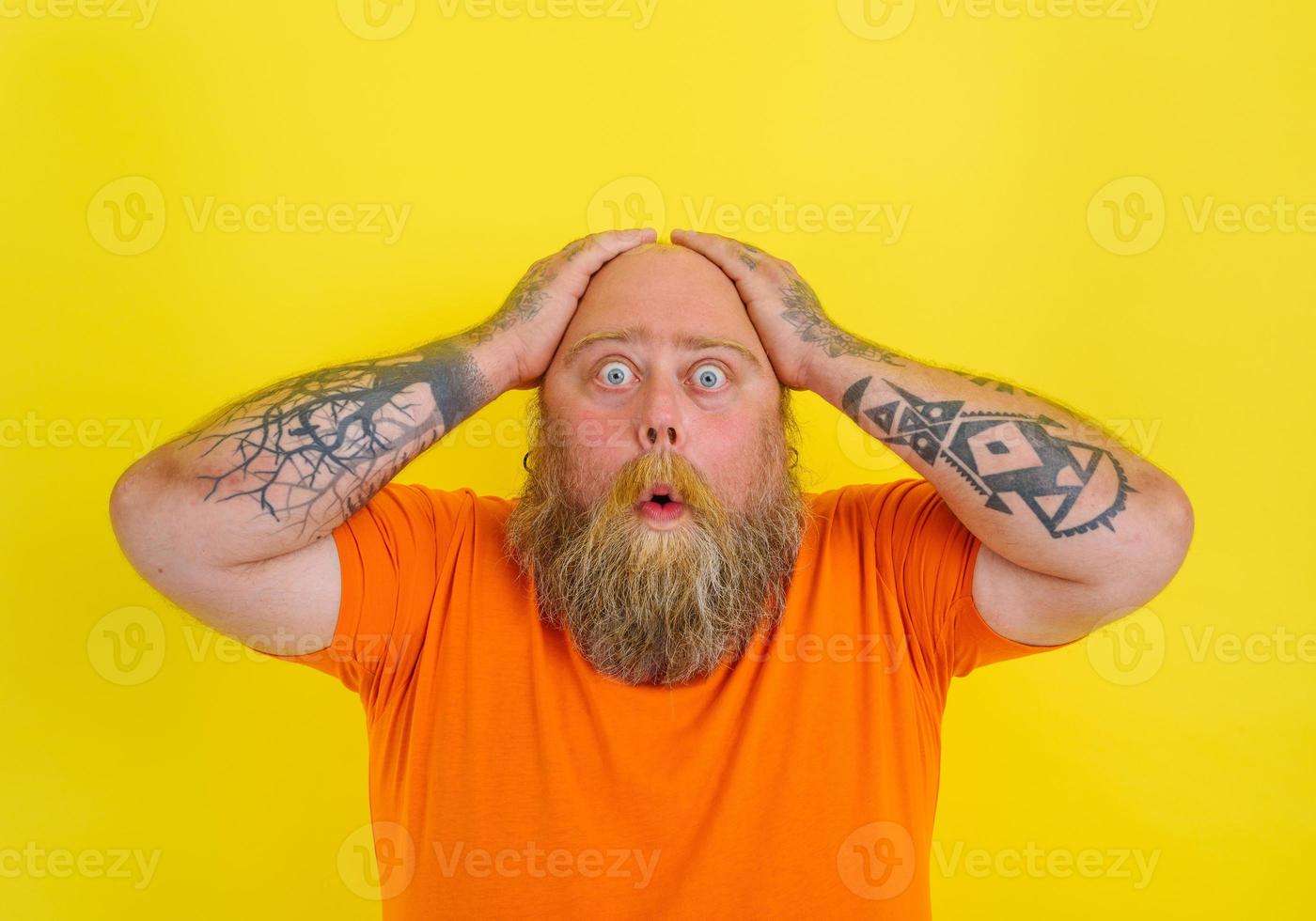 Afraid man with beard and tattoos is worried about something photo