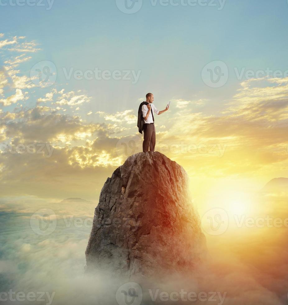 Businessman works on tablet with internet connection over a mountain photo