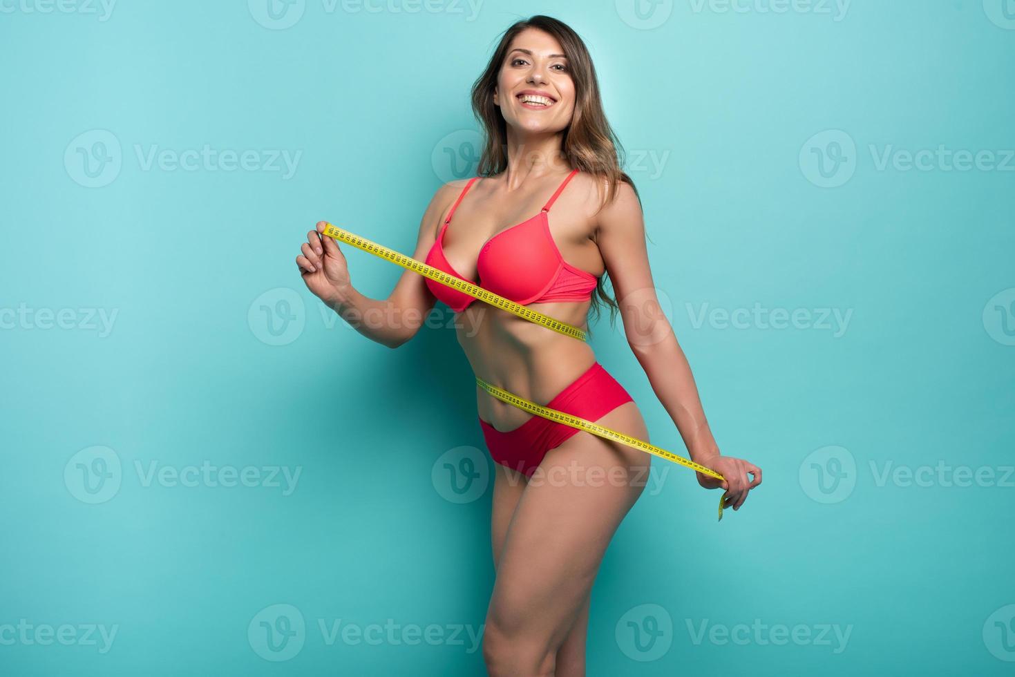 Girl measures with the meter the diet results. Happy and joyful expression. Cyan background photo