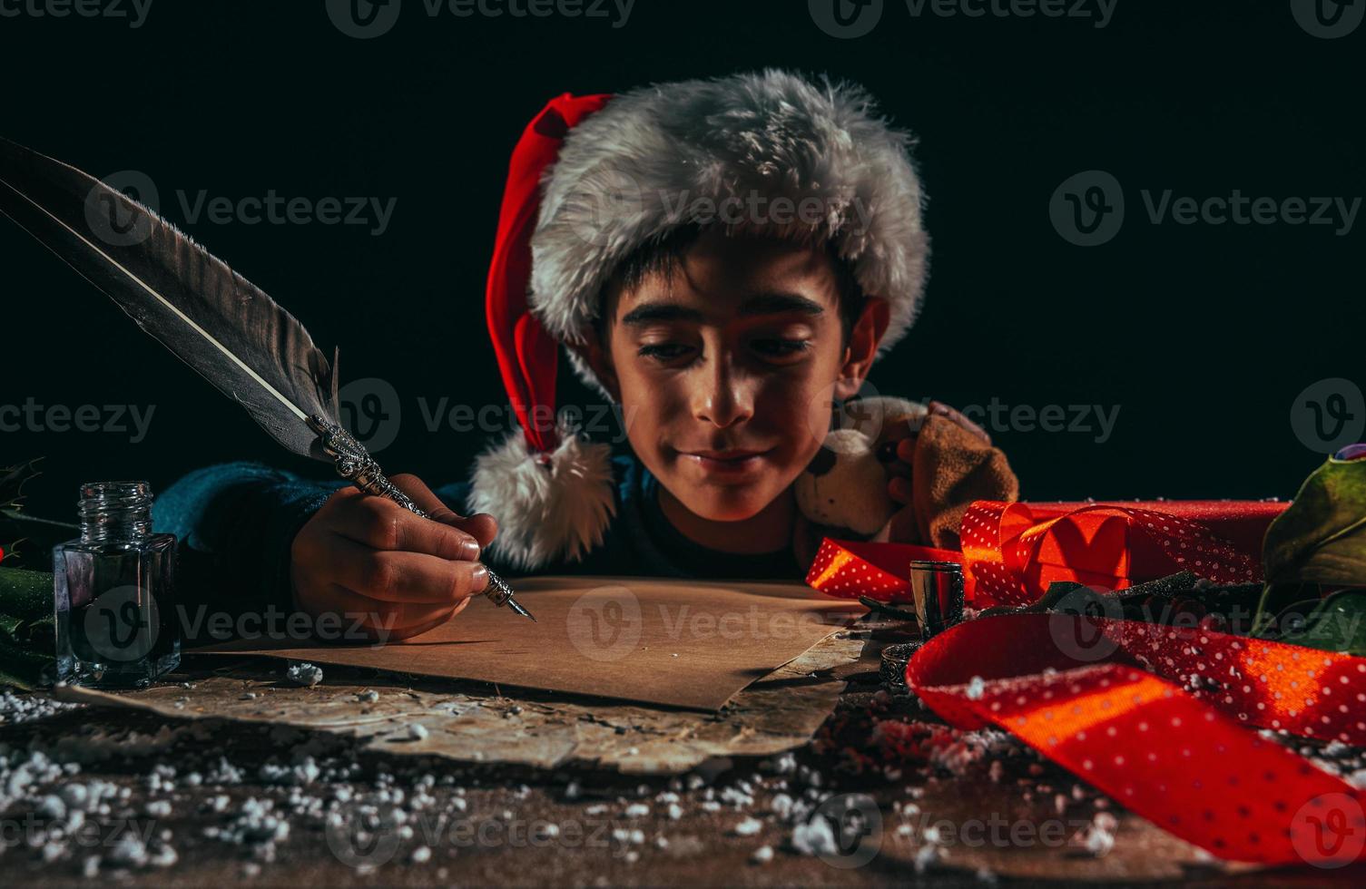 Child with Christmas hat writes a letter to santa claus for gifts photo