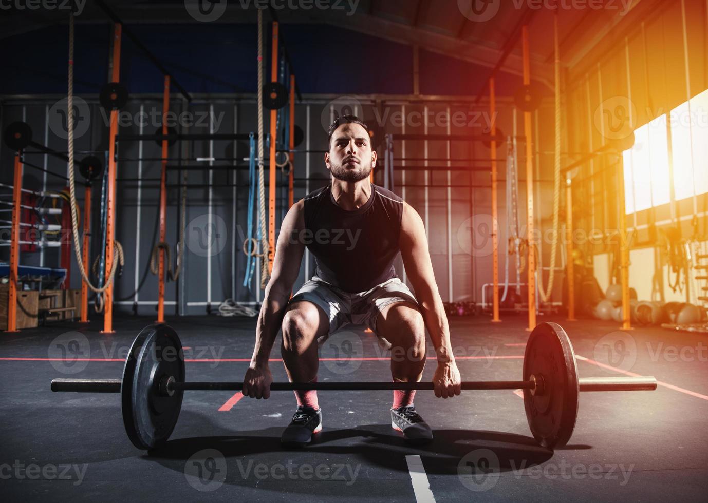 Athletic man works out at the gym with a barbell photo