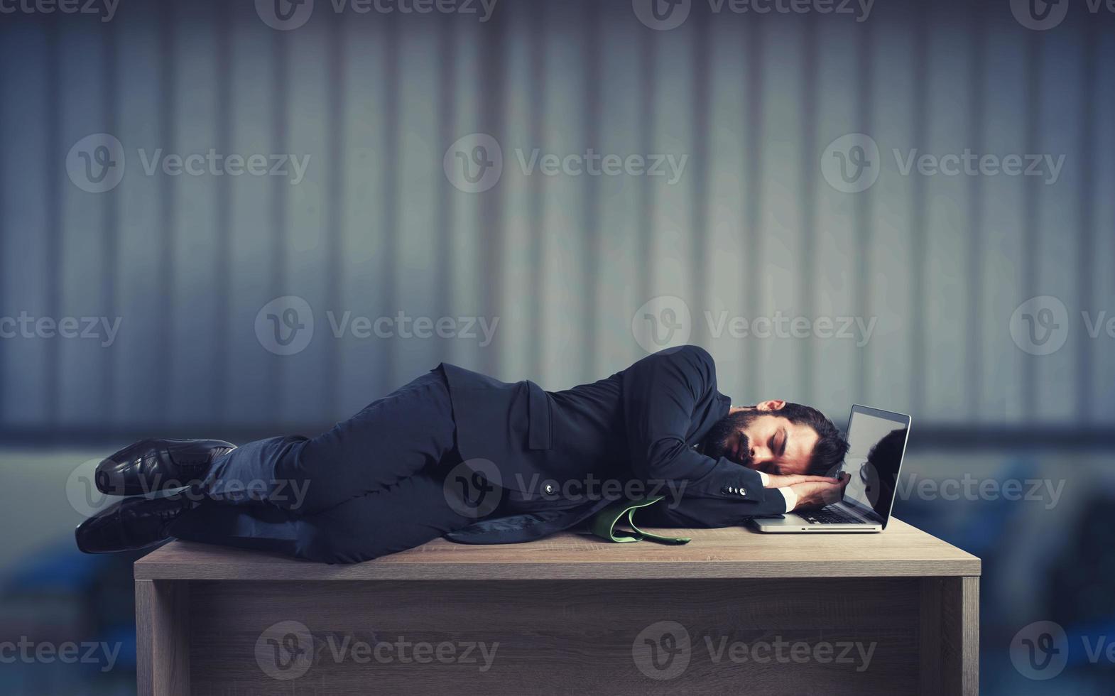 Businessman sleeping over a desk due to overwork photo