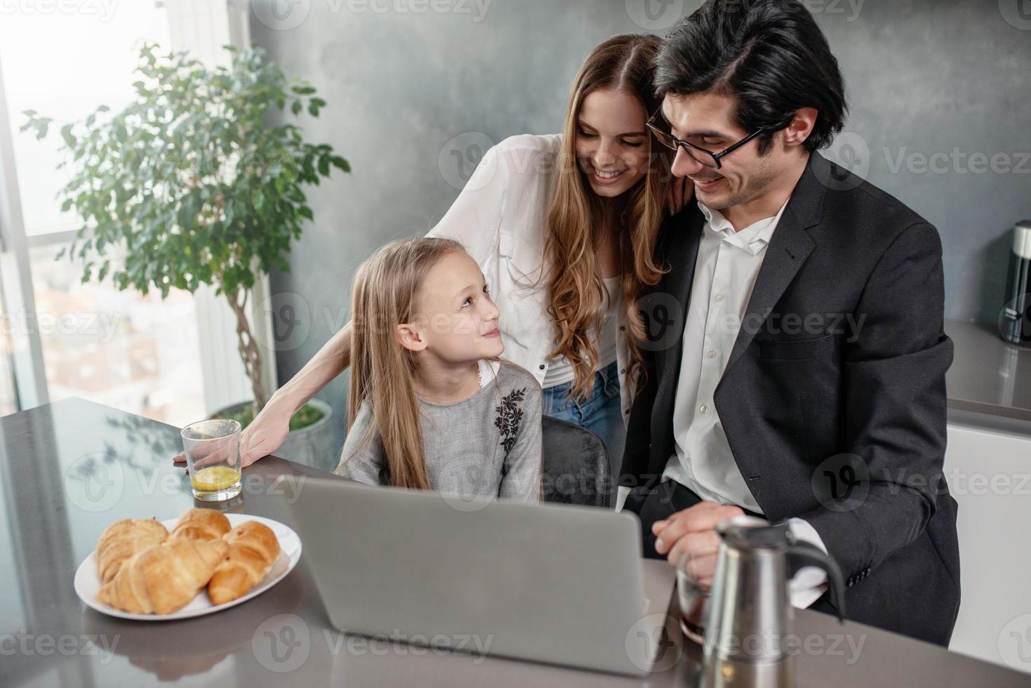 Happy little girl watching a movie on the computer with her father and mother photo