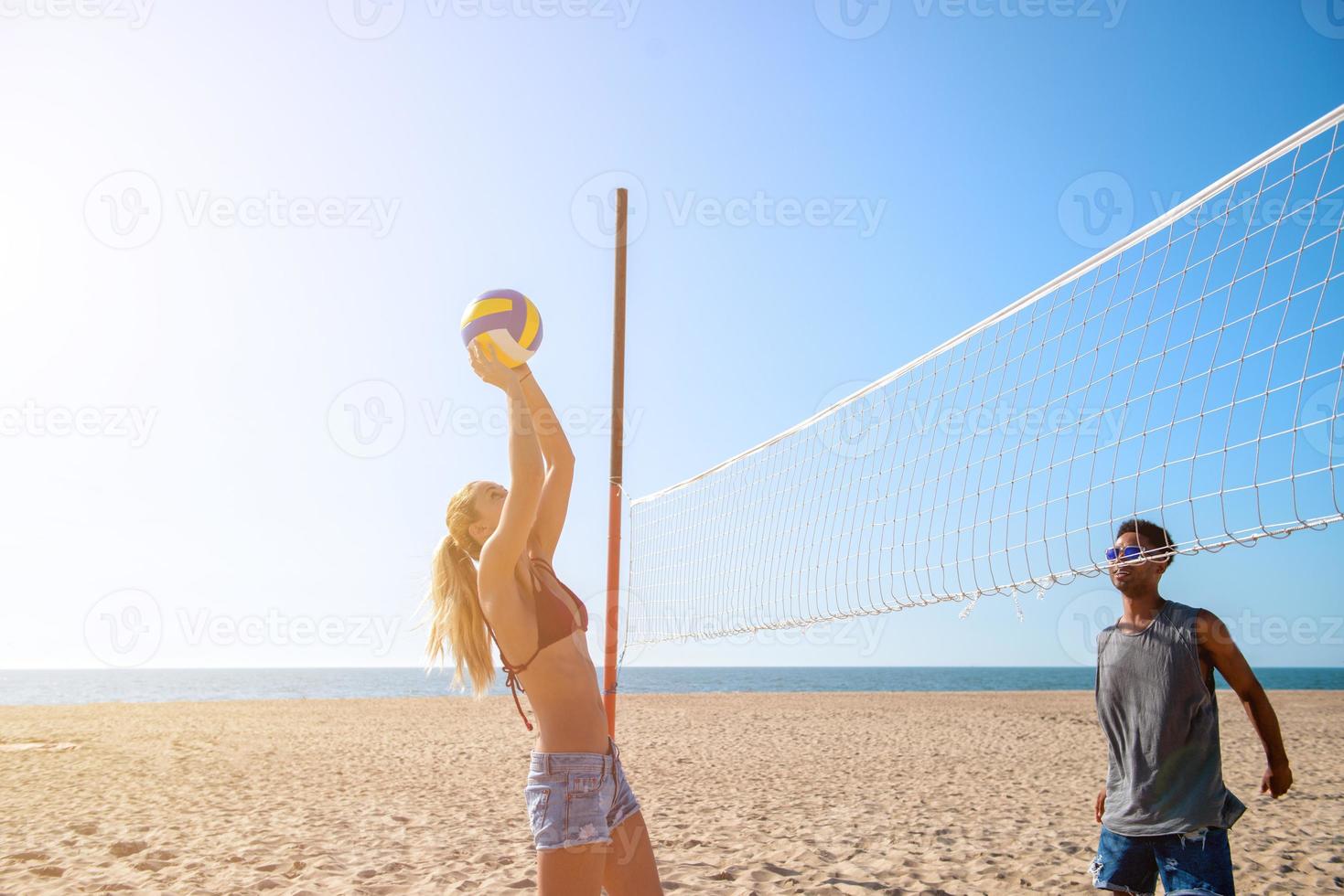 Group of friends playing at beach volley at the beach photo