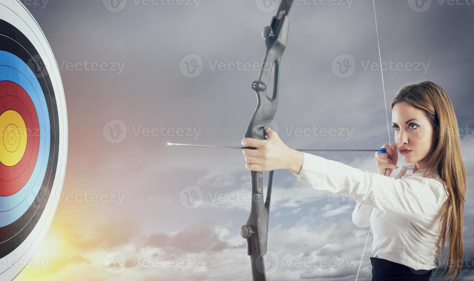 mujer de negocios con arco y flecha señalando el centrar de el objetivo. foto