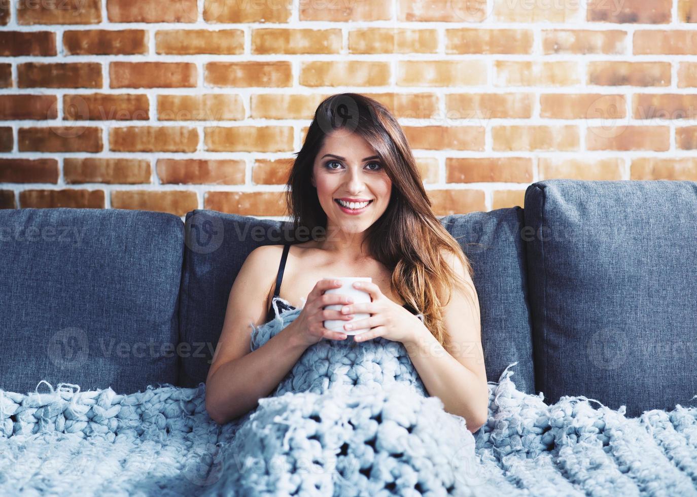 Brunette girl drinking cappuccino for breakfast on a sofa. Concept of relax. photo