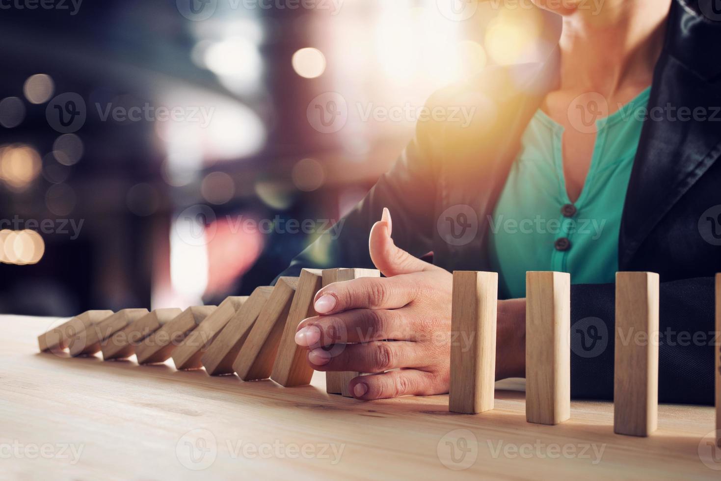 Businesswoman stops a chain fall like domino game. Concept of preventing crisis and failure in business. photo