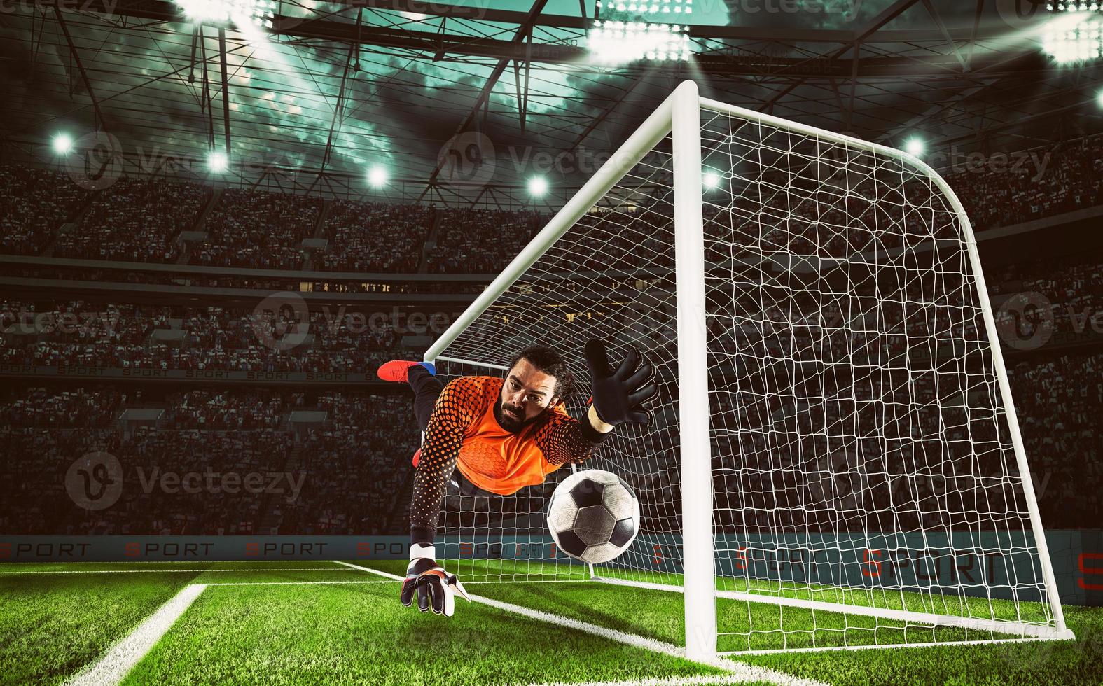 Goalkeeper in orange uniform catches the ball in the stadium during a football game photo