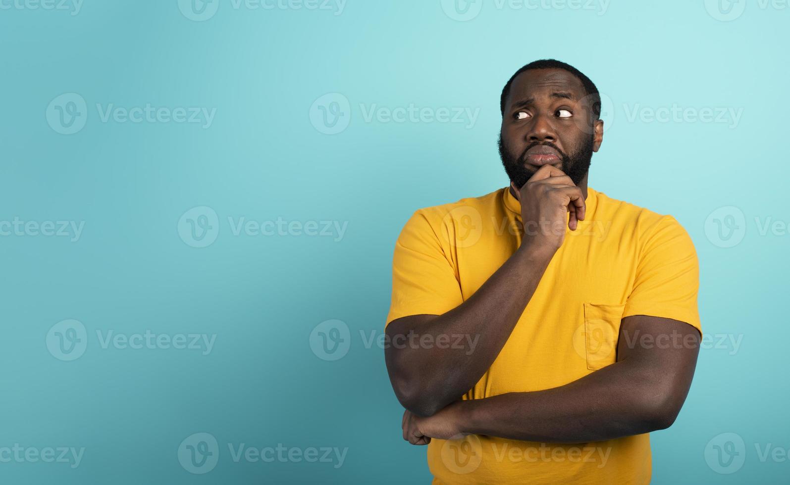 Confused and pensive expression of a boy with many questions . cyan colored background photo