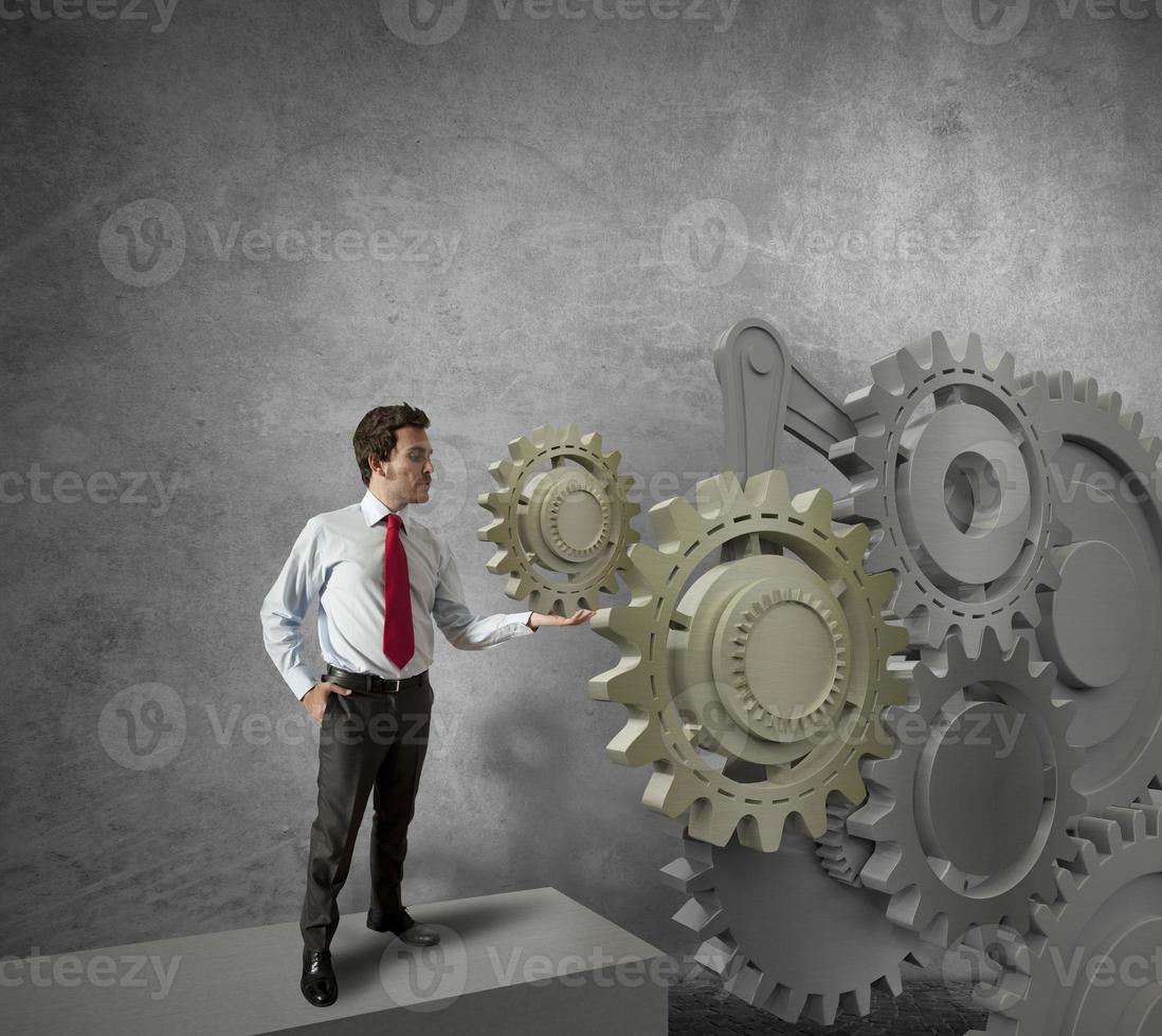 Businessman turning a gear system photo
